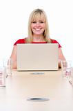 Businesswoman sitting in boardroom with laptop smiling