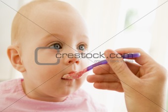 Mother feeding baby food to baby
