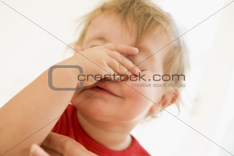 Baby indoors putting hand over face