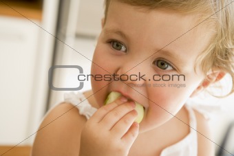 Young girl eating apple indoors