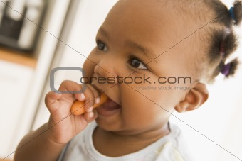 Young girl eating carrot indoors