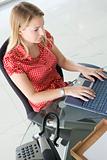 Businesswoman sitting in office typing on laptop