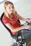 Businesswoman sitting in office typing on laptop smiling