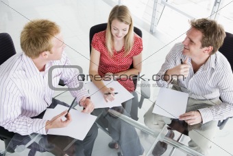 Three businesspeople in a boardroom looking at paperwork