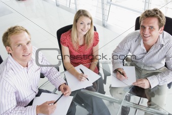 Three businesspeople in a boardroom with paperwork smiling
