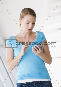 Woman standing in corridor using personal digital assistant