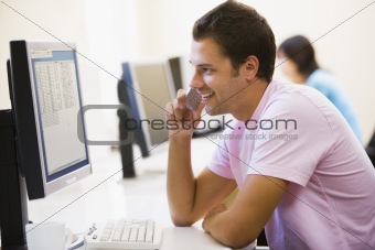 Man in computer room using cellular phone and smiling
