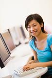 Woman sitting in computer room typing and smiling