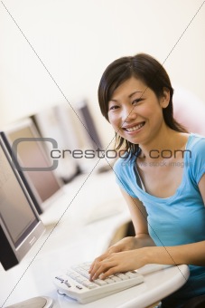 Woman sitting in computer room typing and smiling