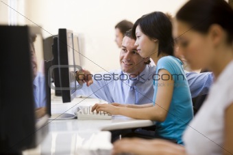 Man assisting woman in computer room smiling