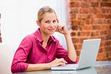 Businesswoman sitting in office with laptop smiling