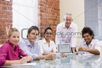Five businesspeople in boardroom with laptop