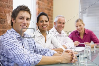 Four businesspeople in boardroom smiling