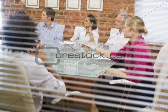 Five businesspeople in boardroom through window