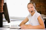 Businesswoman wearing headset sitting in office smiling
