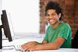Businessman in office typing on computer smiling
