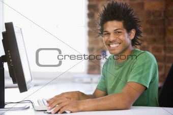 Businessman in office typing on computer smiling