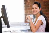 Businesswoman in office drinking coffee and smiling
