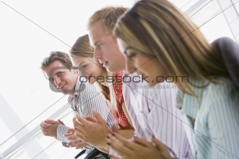 Four businesspeople applauding indoors smiling