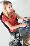 Businesswoman in office typing on computer and smiling