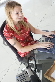 Businesswoman in office typing on computer and smiling
