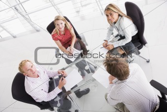 Four businesspeople in boardroom with paperwork smiling