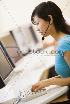 Woman wearing headset sitting in computer room typing
