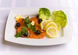 Salty salmon decorated with salad leaves, lemon slice, olives an