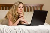 Woman on laptop on bed