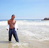 Handsome African American Man Removing His Shirt in the Ocean 