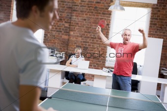 Two men in office space playing ping pong