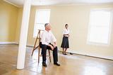 Man sitting on ladder in empty space with woman holding paper
