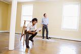 Man sitting on ladder in empty space holding paper with other ma