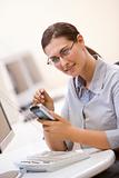 Woman in computer room using personal digital assistant and smil