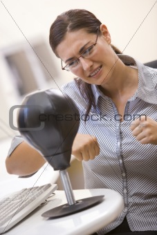Woman in computer room using small punching bag for stress relie