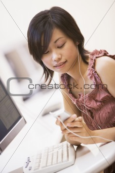 Woman in computer room listening to MP3 player