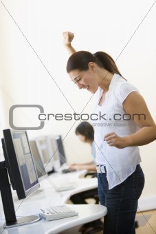 Woman standing in computer room cheering and smiling