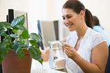 Woman in computer room watering plant smiling