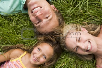 Family lying in grass smiling