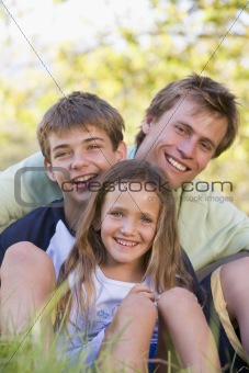 Man with two children sitting outdoors smiling