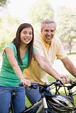 Man and girl on bikes outdoors smiling