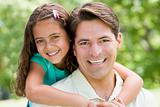 Man and young girl embracing outdoors smiling