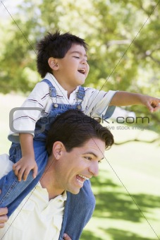 Man giving young boy shoulder ride outdoors smiling