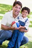 Man and young boy outdoors with football smiling