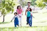 Family running outdoors holding hands and smiling