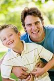 Man and young boy outdoors embracing and smiling