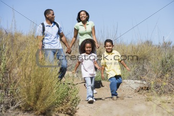 Family walking on path holding hands and smiling