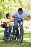 Man and young boy on bikes outdoors smiling
