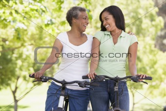Two women on bikes outdoors smiling