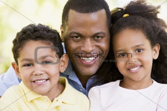 Man and two young children outdoors smiling